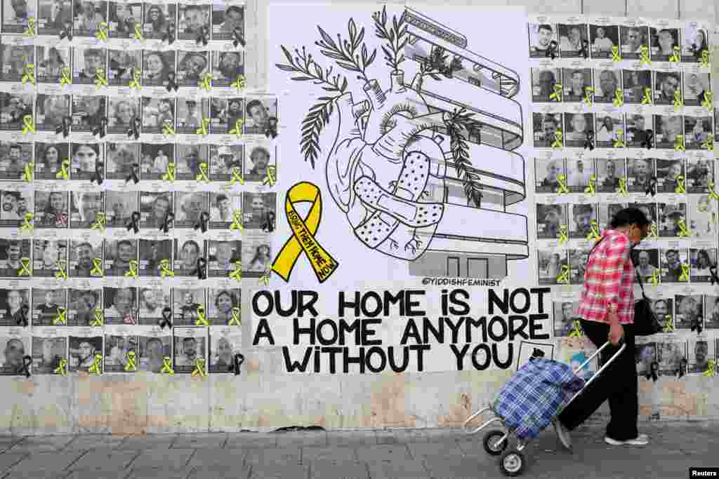 A woman walks next to memorial pictures of hostages kidnapped during the deadly October 7 attack on Israel by Hamas, in Tel Aviv, Israel.