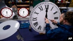 FILE - Ian Roders fastens the hands to a clock at Electric Time Company, Nov. 1, 2022, in Medfield, Massachusetts. Most of the U.S. will move their clocks ahead one hour on March 12 for daylight saving time. 