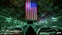 This photo taken aboard a U.S. military transport aircraft on March 21, 2024 shows humanitarian aid packages destined for the Gaza Strip being loaded onto the aircraft before leaving Al Udeid Air Base.