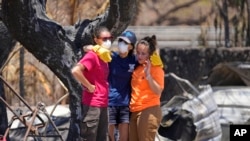 Women hug after digging through rubble of a home destroyed by a wildfire in Lahaina, Hawaii, Aug. 11, 2023.