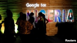 FILE — Participants walk past glowing signs during a conference tagged "Google for Nigeria" in Lagos, Nigeria, July 27, 2017.