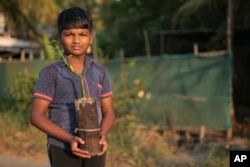 T. M. Akanitth, grandson of T. P. Murukesan, holds a mangrove sapling grown at their home nursery on Vypin Island, in Kochi, Kerala state, India, on March 4, 2023.