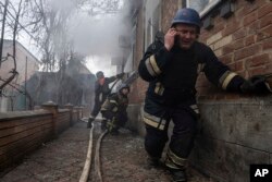 A rescue worker speaks on the phone while his team puts out a fire in a house which was shelled by Russian forces at the residential neighbourhood in Kostiantynivka, Ukraine, Friday, March 10, 2023.