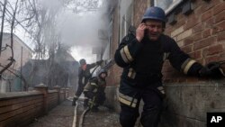A rescue worker speaks on the phone while his team puts out a fire in a house shelled by Russian forces in Kostiantynivka, Ukraine, March 10, 2023.