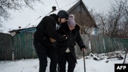 A volunteer Andrey (L), 38, helps Lydia Ivanovna, 62, to evacuate in Chasiv Yar, Feb. 15, 2023, amid the Russian invasion of Ukraine.