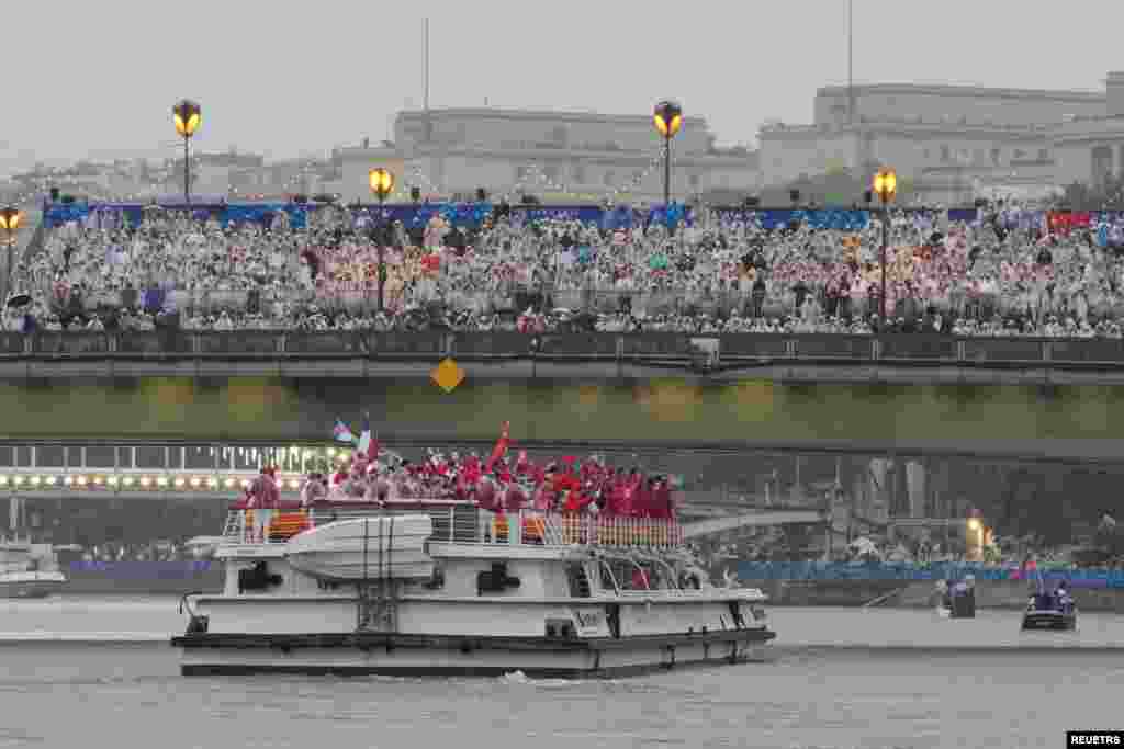 Tim China dan Kanada berlayar menyusuri Sungai Seine saat penonton menyaksikan di tengah hujan di Paris saat upacara pembukaan Olimpiade Musim Panas 2024, 26 Juli 2024. (Foto: Morry Gash/Pool via Reuters)