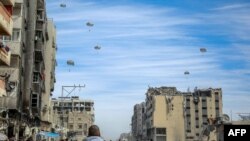 Palestinians run along a street as humanitarian aid is air-dropped in Gaza City, amid the ongoing conflict between Israel and the Hamas militant group. For months, aid workers have warned of an increasingly desperate situation for civilians in the area.
