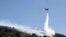 A firefighting helicopter throws water over a wildfire at Keratea area, southeast of Athens, Greece, June 30, 2024. 