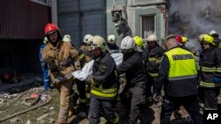 Firefighters carry a body recovered from the rubble of a residential building that was hit during a Russian attack in Uman, central Ukraine, April 28, 2023.