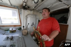 Fisherman Alexei Grebennikov steers his boat on Lake Balkhash in Kazakhstan on June 18, 2024. 'There are fewer and fewer fish,' he says. 'It's catastrophic; the lake is silting up.'