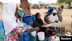 Fatma Dahab Ousman, a Sudanese refugee who fled the violence in her country, sells tea and porridge to other refugees near the border between Sudan and Chad, in Koufroun, Chad, May 1, 2023. 