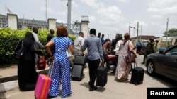Passengers walk with their luggage past soldiers as protesters block the domestic terminal of Murtala Muhammed International airport during a strike over working conditions and wages, in Lagos, Nigeria, April 17, 2023.