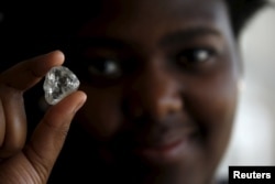 FILE - A visitor holds a diamond during a visit to the De Beers Global Sightholder Sales (GSS) in Gaborone, Botswana, Nov. 24, 2015.