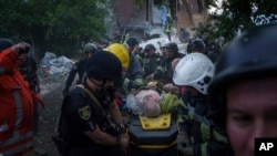 Los equipos de rescate y los agentes de policía transportan a una persona herida en una camilla hasta una ambulancia desde un edificio destruido por un ataque aéreo ruso en Járkov, Ucrania, el 10 de junio de 2024.