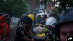 Rescue workers and police officers carry an injured person by a stretcher to an ambulance from a building which was destroyed by a Russian airstrike in Kharkiv, Ukraine, June 10, 2024. 