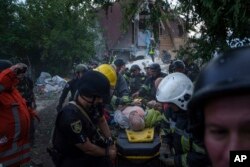 Rescatistas y agentes de policía transportan a una persona herida en camilla a una ambulancia desde un edificio destruido por un ataque aéreo ruso en Járkov, Ucrania, el 10 de junio de 2024.