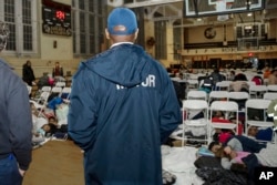 In this photo provided by the Office of the Mayor New York, New York Mayor Eric Adams visits with asylum-seekers taking shelter at James Madison High School, in the Brooklyn borough of New York, Jan. 9, 2024.
