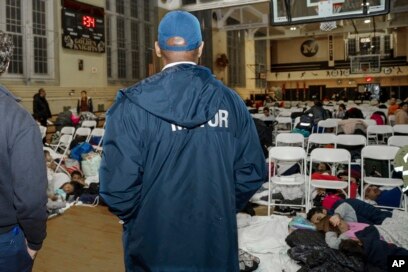 In this photo provided by the Office of the Mayor New York, New York Mayor Eric Adams visits with asylum-seekers taking shelter at James Madison High School, in the Brooklyn borough of New York, Jan. 9, 2024.