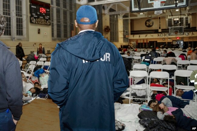 In this photo provided by the Office of the Mayor New York, New York Mayor Eric Adams visits with asylum-seekers taking shelter at James Madison High School, in the Brooklyn borough of New York, Jan. 9, 2024.