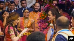 Nita Ambani, left, wife of Reliance Industries Chairman Mukesh Ambani along with his son Anant Ambani, right, and his fiancée Radhika Merchant, center, greets guests during pre-wedding ceremony at their residence Antilia in Mumbai, India, July 3, 2024.(AP Photo/Rafiq Maqbool)