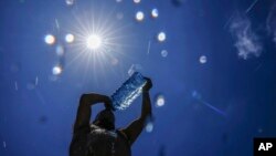 FILE - A man pours cold water onto his head to cool off on a sweltering hot day in the Mediterranean Sea in Beirut, Lebanon, July 16, 2023. 