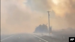 A motorist drives past the Gwen fire on Highway 3 outside of Juliaetta, Idaho on July 25, 2024. Multiple communities in Idaho have been evacuated after lightning strikes sparked fast-moving wildfires. (William Howard via AP)