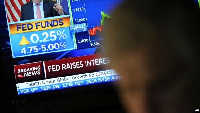 Traders work on the floor of the New York Stock Exchange in New York, on March 22, 2023. News on the Federal Reserve interest rate hike appears on a monitor in the background.