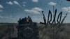 2023 年 8 月 13 日，乌克兰顿涅茨克地区巴赫穆特附近，乌克兰士兵乘坐着一辆装甲运兵车。跟在他们后面的车辆的挡风玻璃上贴着乌克兰国家的象征三叉戟图案。