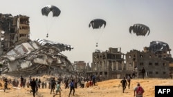 Sejumlah warga di utara Jalur Gaza tampak berlari untuk mengambil paket bantuan yang diberikan lewat udara pada 23 April 2024. (Foto: AFP)