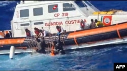 Foto selebaran ini diambil pada 5 Agustus 2023 oleh Penjaga Pantai Italia, dirilis 6 Agustus 2023, menunjukkan penyelamat membantu migran naik perahu penyelamat selama operasi di selatan Lampedusa. (Penjaga Pantai Italia / Guardia Costiera / AFP)