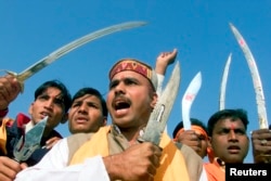FILE - Indian activists of the hardline Hindu group Bajrang Dal wield their swords and knives, while shouting slogans in the northern Indian city of Chandigarh, Dec. 6, 2003.