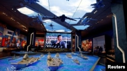北京的中国军事博物馆内在中国领导人习近平的巨幅电子屏幕前展示的军事装备模型。（2022年10月8日）