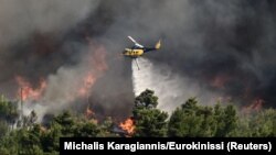 A firefighting helicopter makes a water drop as a wildfire burns in Varnava, near Athens, Greece, Aug. 11, 2024. 