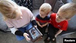 ILUSTRASI - Charlie dan Jack Walker mendengarkan cerita yang diposting oleh staf Little Stars Childcare di aplikasi taman kanak-kanak dan Facebook mereka di Newcastle-under-Lyme , Inggris, 24 Maret 2020. (REUTERS/Carl Recine)