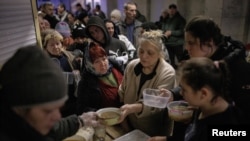 Sejumlah warga menerima bantuan makanan dari para relawan di sebuah stasiun metro yang dijadikan sebagai tempat penampungan di utara Kharkiv, Ukraina, pada 24 Maret 2022. (Foto: Reuters/Thomas Peter)