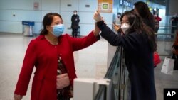 An arriving international passenger, left, is greeted at the international arrivals area at Beijing Capital Inernational Airport in Beijing, March 15, 2023, the day China reopened its borders to tourists and resumed issuing all visas. 