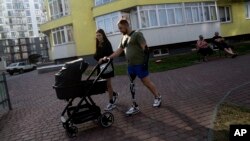 Mykhailo Yurchuk, former Ukrainian paratrooper of 95th brigade and his wife, Maria, go for a walk with their newborn daughter, Olivia, near their house in Lviv, Ukraine, Aug. 23, 2023.
