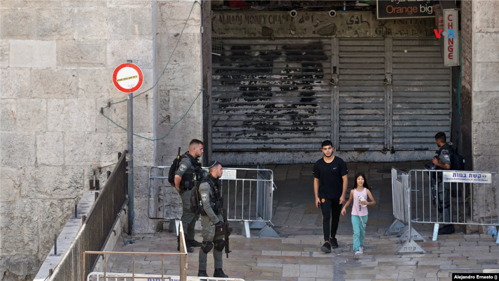 Un adolescente y una niña caminan entre soldados israelíes que custodian los accesos a la Ciudad Vieja de Jerusalén, fuertemente militarizada este 13 de octubre de 2023, cuando exlíderes de Hamás han llamado a un día de protestas en apoyo a la causa palestina en todo el mundo.&nbsp;