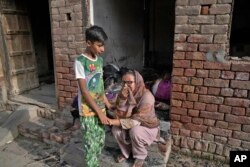 Seorang anak laki-laki menghibur ibunya yang menangis setelah menyaksikan rumahnya dirusak oleh massa Muslim yang marah di Jaranwala di distrik Faisalabad, Pakistan, Kamis, 17 Agustus 2023. (Foto: AP)