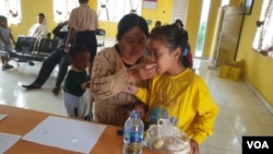 Seorang ibu membantu anaknya meminum obat untuk pengobatan penyakit schistosomiasis di Puskesmas Maholo, Lore Timur, Sabtu (11/2) (Foto: VOA/Yoanes Litha).