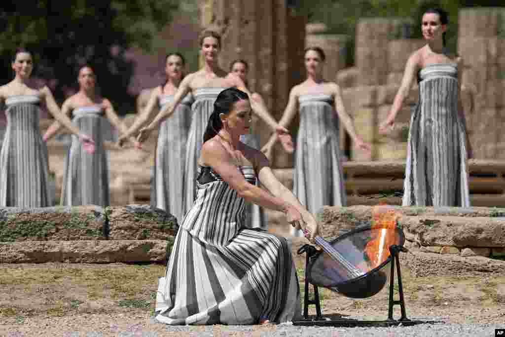 Actress Mary Mina, playing a priestess, lights the flame during the final dress rehearsal of the flame-lighting ceremony for the Paris Olympics, at the Ancient Olympia site, Greece.