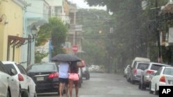 People walk in the rain brought by Tropical Storm Franklin in Santo Domingo, Dominican Republic, Aug. 23, 2023.