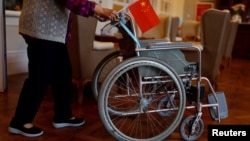 FILE - A resident pushes a wheelchair while holding a Chinese flag at Heyuejia, a care home for the elderly, in Beijing on May 26, 2021. China fully rolled out its private pension system on Dec. 15, 2024.