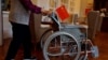 北京一家养老院的老人手握国旗推动一个轮椅。（2021年5月26日）