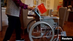 资料照：北京一家养老院的老人手握中国国旗推动一个轮椅。（2021年5月26日）