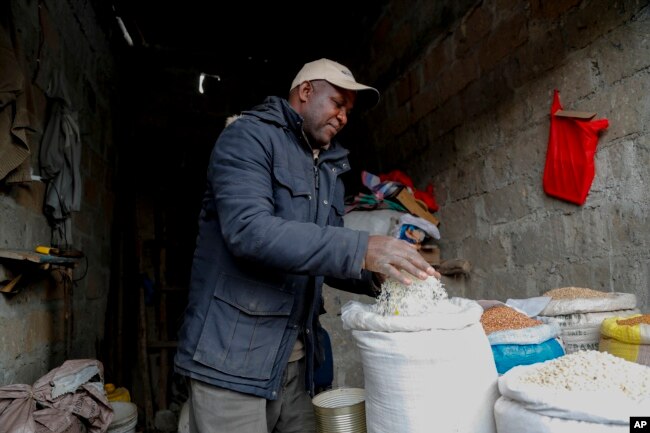 Vendor Francis Ndege measures rice at his stall in the Toi Market, Nairobi, Kenya on Wednesday, Aug. 9, 2023. (AP Photo/Brian Inganga)