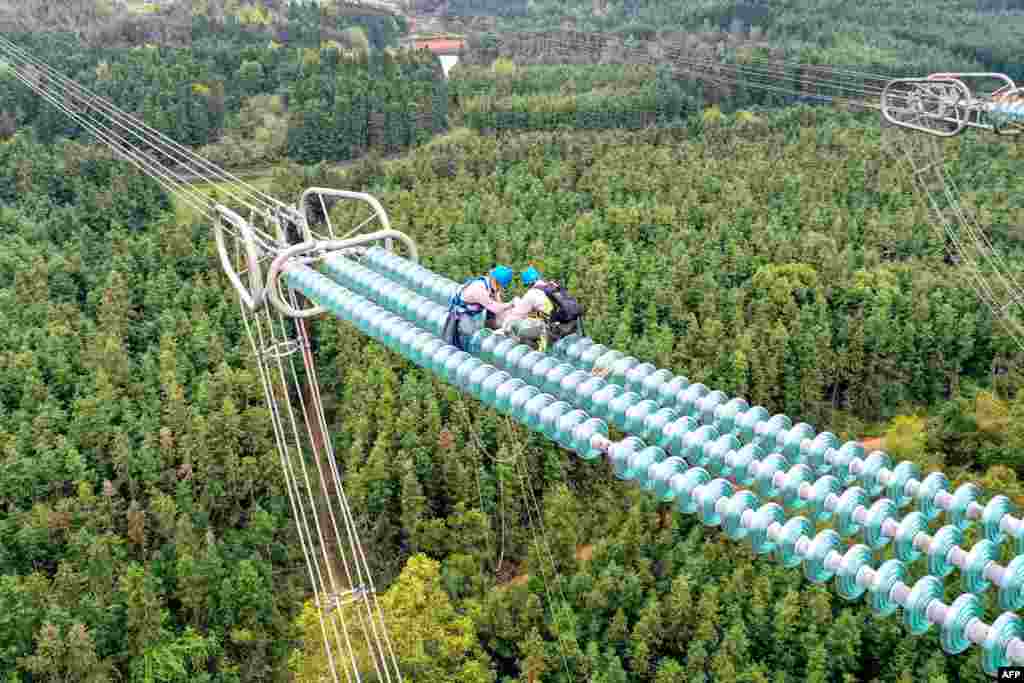 Workers fix cables on a transmission tower in Yichun, in central China&#39;s Jiangxi province.