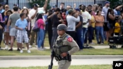 A law enforcement officer walks as people are evacuated from a shopping center where a shooting occurred May 6, 2023, in Allen, Texas. 