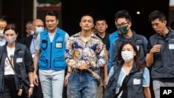 被判无罪的前民主派区议员李予信（左三）在47人案被告中被判无罪后离开香港西九龙裁判法院。（2024年5月30日）