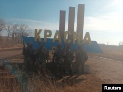 An image, released by founder of Russia's Wagner Group Yevgeny Prigozhin's press service, shows what it said to be Wagner fighters posing for a picture at the entrance sign to the village of Krasna Hora near the embattled city of Bakhmut, Ukraine, in this handout picture released Feb. 12, 2023.